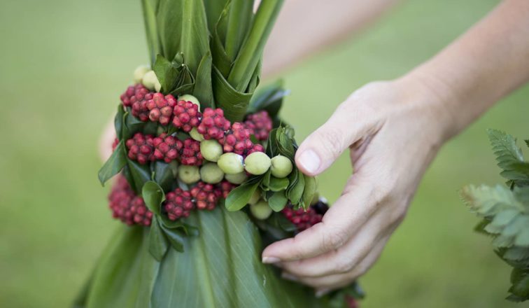 Hands reaching out to tropical plants and leis